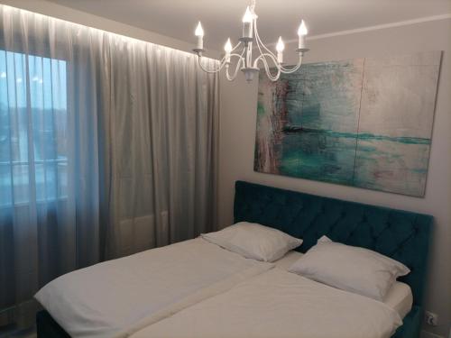a bedroom with a bed with a chandelier and a window at Lighthouse Apartment in Gąski