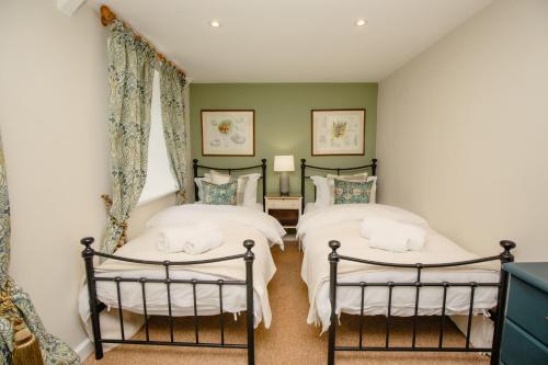 Duas camas num quarto com paredes verdes em Gardeners Cottage - Rudge Farm Cottages em Bridport