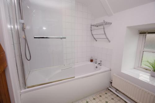 uma casa de banho branca com uma banheira e um chuveiro em Gardeners Cottage - Rudge Farm Cottages em Bridport