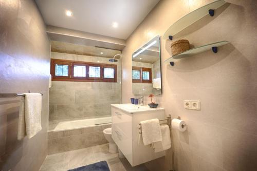 een badkamer met een wastafel, een toilet en een bad bij Chalet Tres Mares, Cala Millor in Son Servera