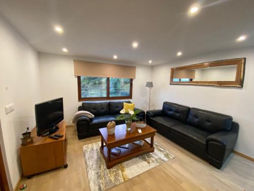 a living room with a black leather couch and a television at Penha D'Águia Villa in Porto da Cruz