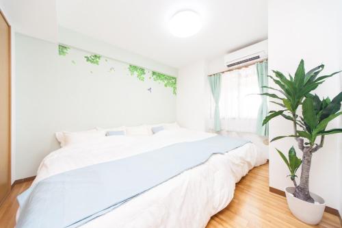 a white bedroom with a large bed and a potted plant at Mansion Kitanomachi Room 408 - Vacation STAY 64438v in Awaji