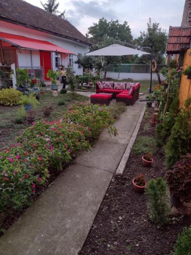 a garden with red couches and flowers and an umbrella at T.I.M. in Bela Crkva