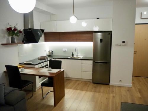 a kitchen with a table and a stainless steel refrigerator at Zdrowa Apartment in Wilanów in Warsaw