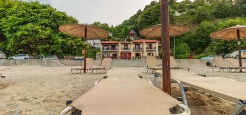 a wooden table with umbrellas and chairs on a beach at Pelagos Hotel in Agios Ioannis Pelio
