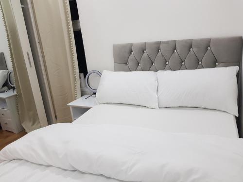 a bed with white sheets and a gray headboard at Elegant room In a private House in Rotherham