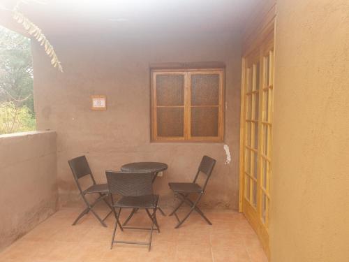 a table and chairs in a room with a window at Hostal Candelaria in San Pedro de Atacama