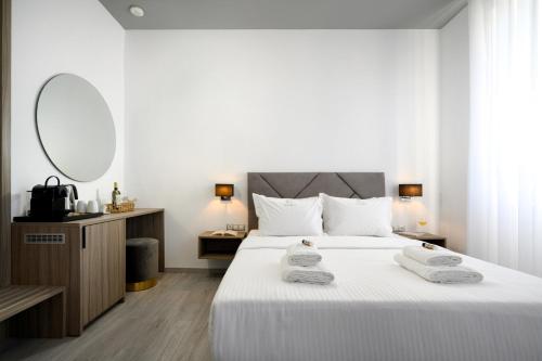 une chambre avec un grand lit blanc avec des serviettes dessus dans l'établissement Amalphi Corfu City Living by Konnect, à Corfou