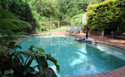 una piscina en un patio con 2 sillas en Sunshine Valley Cottages, en Woombye