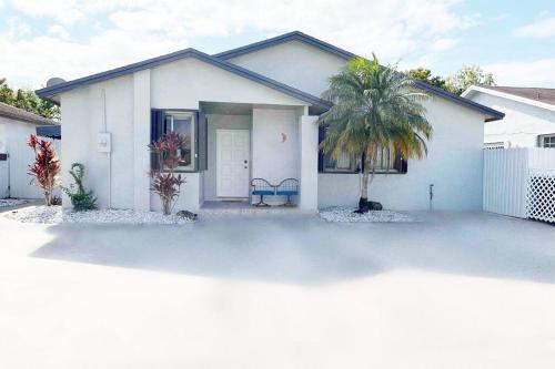 a white house with a palm tree in front of it at Amazing & cozy Duplex near Zoo Miami ! in Miami
