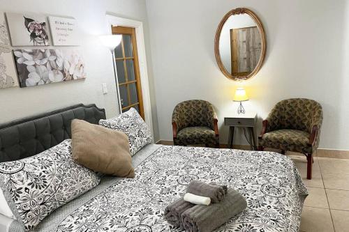 a bedroom with a bed and two chairs and a mirror at Amazing & cozy Duplex near Zoo Miami ! in Miami