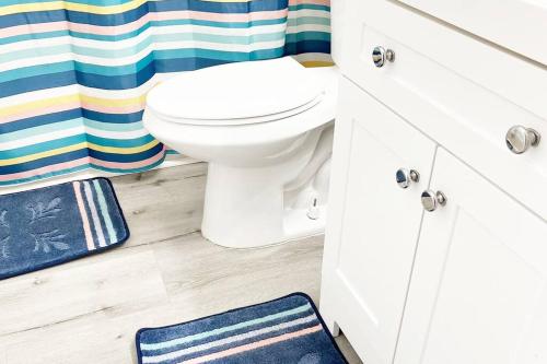 a bathroom with a white toilet and a blue shower curtain at Amazing & cozy Duplex near Zoo Miami ! in Miami