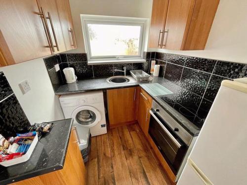 a small kitchen with a sink and a washing machine at The Nest in Hemsby