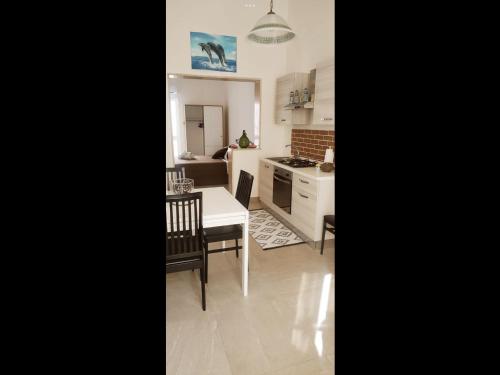 cocina y comedor con mesa blanca y sillas en LEVANTE APPARTAMENTO SUL MARE en Porto Cesareo