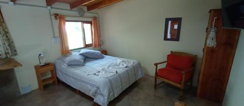 um quarto com uma cama e uma cadeira vermelha em Choique em San Carlos de Bariloche