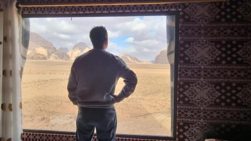 a man looking out of a window at the desert at Qais Camp Wadi Rum in Wadi Rum