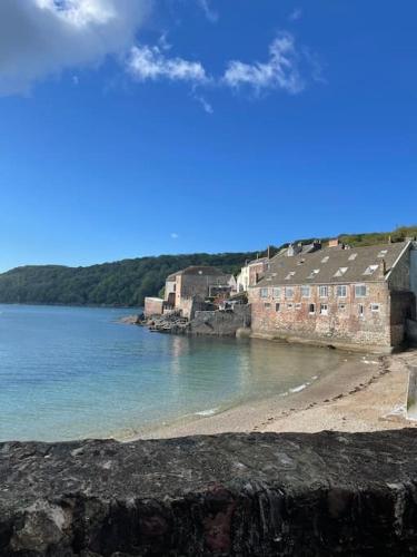 a group of buildings on a beach next to the water at The View, Kingsand, luxurious seafront penthouse apartment with sun trap balcony and incredible sea views in Kingsand