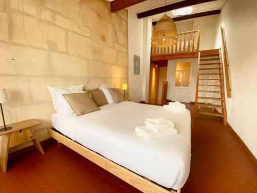 una camera da letto con un grande letto bianco e una scala di "La paisible" Maison vue sur le Rhône Arles a Arles