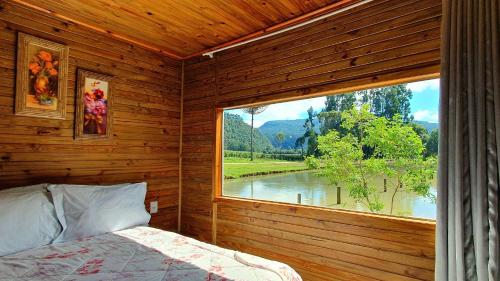 a bedroom with a window with a view of a river at Pousada Mato Verde - Urubici - SC in Urubici