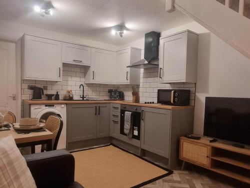a kitchen with white cabinets and a living room at Cosy Moat House Cottage #3 in Pembroke