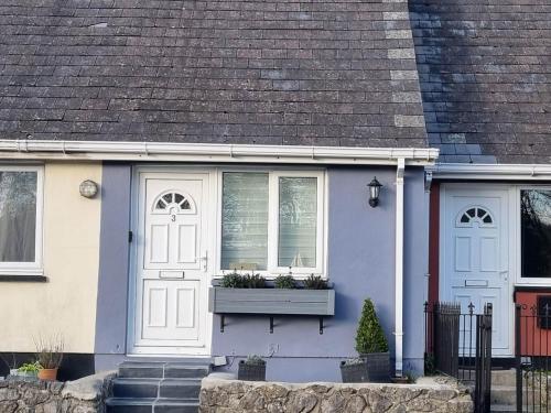 a blue and white house with a window at Cosy Moat House Cottage #3 in Pembroke