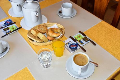 a table with a cup of coffee and a basket of bread at Hotel El Jardin Dante in Tilcara