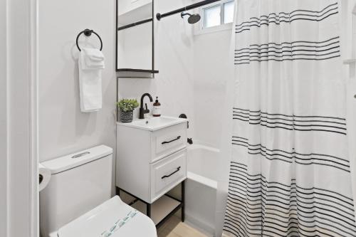 a white bathroom with a toilet and a shower at Loopin Around Atlantic City Luxe 5BR Townhouse in Orange Loop in Atlantic City