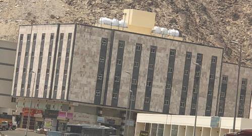 een groot gebouw met veel ramen voor een berg bij Haven in Mekka