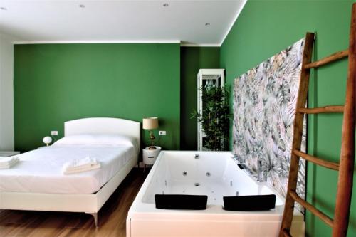 a green bedroom with a bed and a bath tub at COMÓ EXCLUSIVE in Aprilia