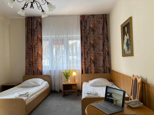 a hotel room with two beds and a laptop on a desk at Karat in Warsaw