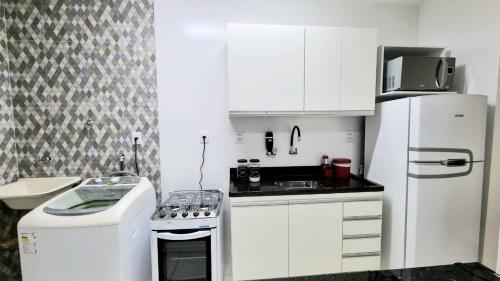 a white kitchen with a stove and a refrigerator at Apartamento aconchegante, em uma das praias mais bonitas do ES in Serra