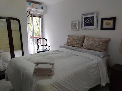Dormitorio blanco con cama grande y espejo en departamento completo en nueva Córdoba en Córdoba