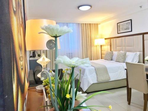 a hotel room with a bed and a table with flowers at Attractive studio with Luxury bed Good for 1-4pax High speed WiFi with Netflix Free Pool & Parking in Suba