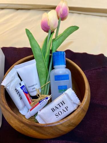 a wooden bowl with toiletries and a bottle of soap and flowers at Attractive studio with Luxury bed Good for 1-4pax High speed WiFi with Netflix Free Pool & Parking in Suba