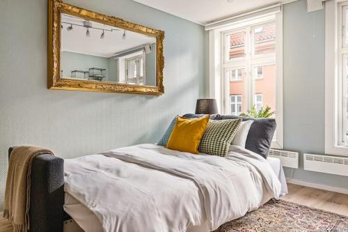 een slaapkamer met een bed met een spiegel aan de muur bij Dinbnb Apartments I Charming 3-Bedroom in the Heart of the City in Bergen