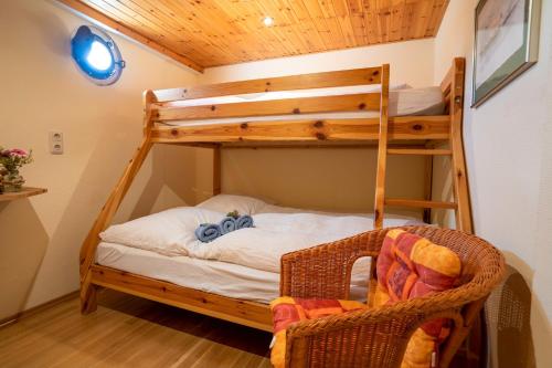 a room with two bunk beds and a wicker chair at Küstenmotorschiff Aventura in Bremen