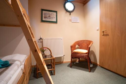 a bedroom with a bunk bed with a ladder and a chair at Küstenmotorschiff Aventura in Bremen