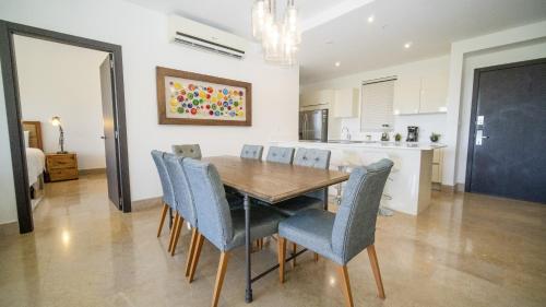 a dining room with a wooden table and blue chairs at Roble Sabana 105 Luxury Apartment - Reserva Conchal in Playa Conchal