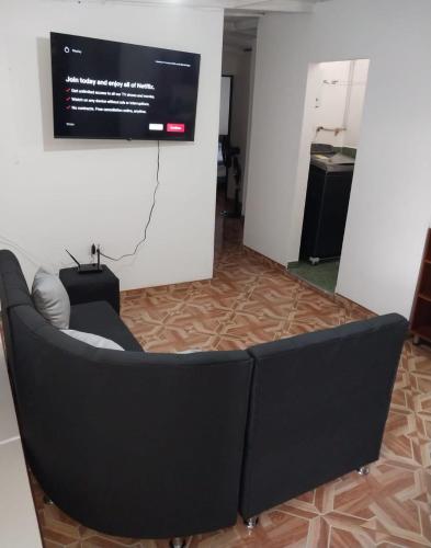 a black couch sitting in a room with a screen at Los balcones lll in Medellín