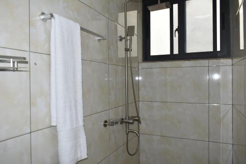 a bathroom with a shower with a towel and a window at BWAMI DUBAI HOTEL KASULU 