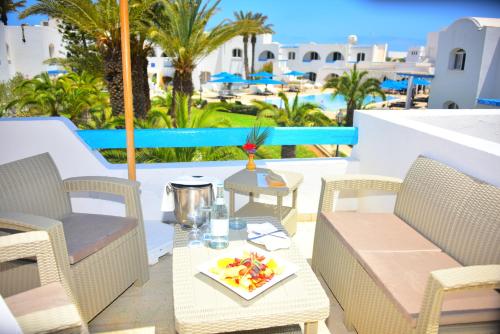 a patio with chairs and a table with a tray of fruit at Zenon Djerba in Midoun