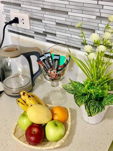 a basket of fruit on a counter with a vase of flowers at Minimalist studio with Luxury bed Good for 1-4pax High speed WiFi with Netflix Free Pool & Parking in Suba