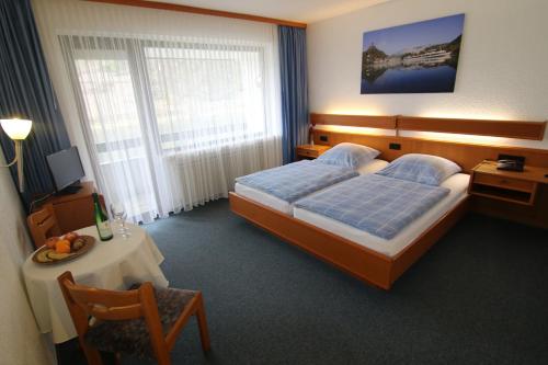 a bedroom with a bed and a table and a chair at Hotel Klasen in Cochem