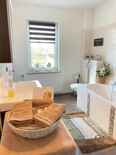 a bathroom with a bath tub and a basket of towels at Gemütliche Fewo mit Garten in Eisenach