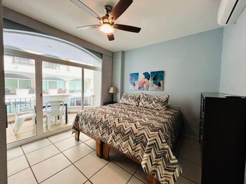 a bedroom with a bed with a ceiling fan and a balcony at Depa frente a la playa by G P S rentas in Mazatlán