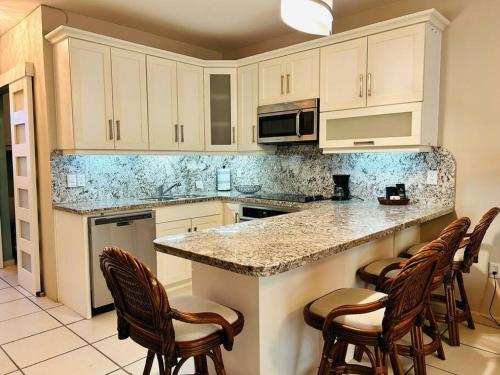 a kitchen with white cabinets and a counter with chairs at Depa frente a la playa by G P S rentas in Mazatlán