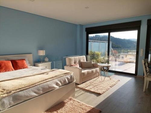 ein Schlafzimmer mit einem Bett und einem Stuhl sowie einem Balkon in der Unterkunft Vila de Campos - Gerês in Vieira do Minho