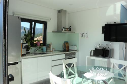 a kitchen with white cabinets and a table and a television at Vila de Campos - Gerês in Vieira do Minho