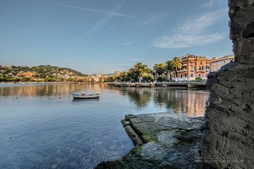 a boat on a river with buildings and palm trees at Hotel Italia e Lido Rapallo in Rapallo