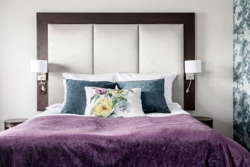 a bed with a purple comforter and pillows at Best Western Plus Gyldenlove Hotell in Kongsberg